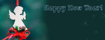 New Year decoration of handmade woody angel on the green background having much space for textの写真素材