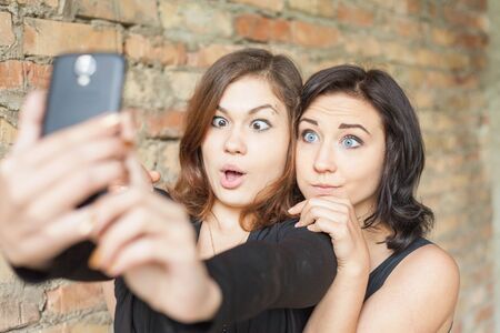 Two happy and funny girls make selfie on mobile phone. They are now a party or birthday, and celebrate fun!の写真素材