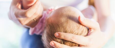 Letterbox format image of mother holding baby headの写真素材