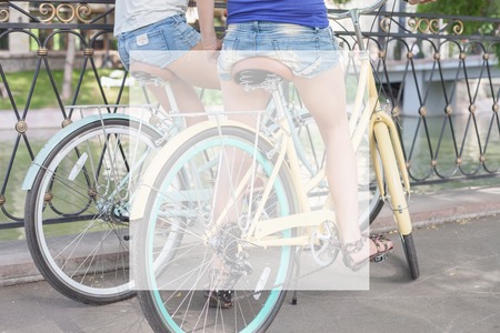 closeup beautiful sexy women dressed in short shorts travel by city vintage bicycle at summer time