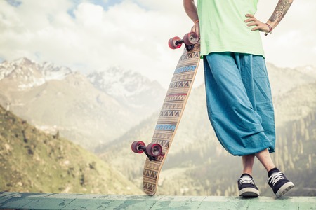 Closeup of Hipster young and handsome man with skateboard outdoor at mountain. World Day of skateboarding. Longboard is the most popular and dangerous youth cultureの写真素材