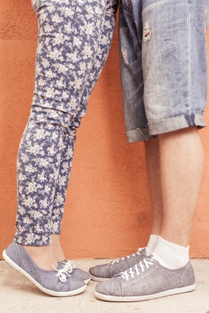 Closeup foot of kissing couple outdoor at street. Shod with same shoes of moccasins or sneakers....