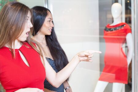 Happy fashion women with bags indoor at the shopping center. She saw sale or elegant dress at boutique. Girl is pointingの写真素材