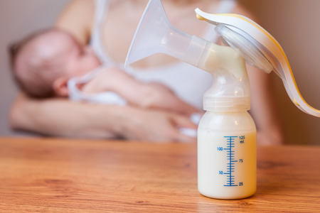 Manual breast pump, mothers breast milk is the most healthy food for newborn baby. Happy mother with baby at backgroundの写真素材