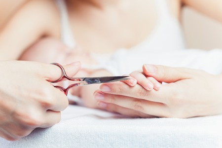 Mom tonsured nails on the hands newborn using nail scissors. Mothercare is most important for baby healthy lifeの写真素材