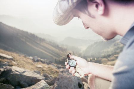 Picture of tourist's hand using a compass. At the background a beautiful valley with tops of mountain. Switzerland.の写真素材