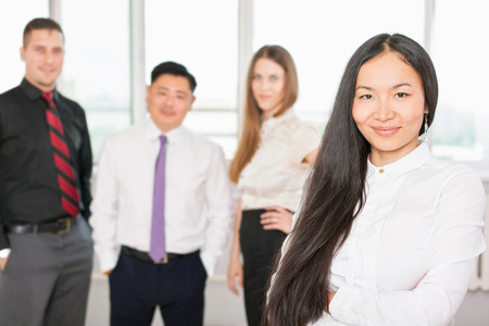 Successful asian business woman with magnificent long hair and there is business team at background....