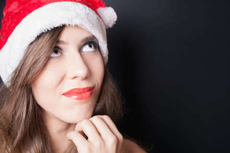 Pretty woman dressed in Santa Claus hat at black background. の写真素材