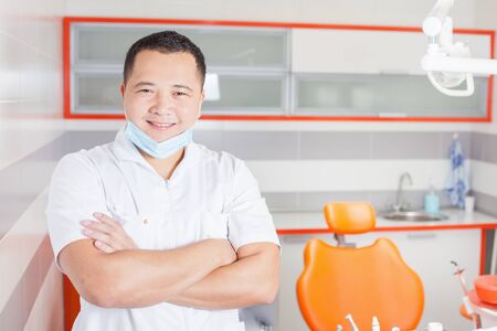Happy and confident dentist doctor at stomatological clinic with modern high-tech furniture design and professional instrumentsの写真素材