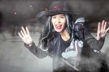 Halloween! Asian witch came to skate. She looks horror at the camera. Woman in fancy dress.