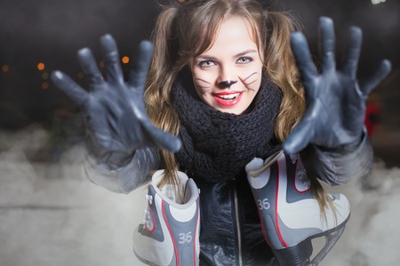 Healthy lifestyle and Halloween! Horror and magic holiday night. Pretty young woman dressed in cat fancy dress. Holiday makeup. Girl holding ice skating bootsの写真素材