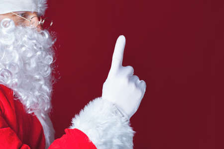 Santa Claus pointing at copy space, red background. Christmas concept. New Year holiday. Shopping discount. Designの写真素材