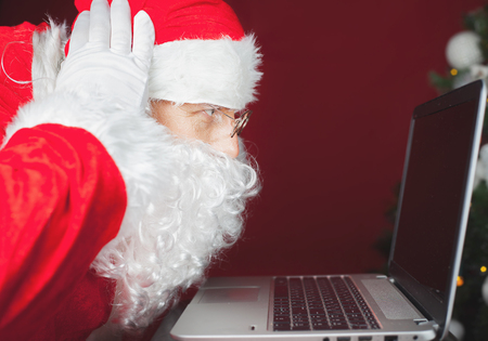 Christmas discount! Santa Claus using laptop computer, looking at screen. Shopping by internet, discount. Emotion, surprise. Christmas holiday. New Yearの写真素材
