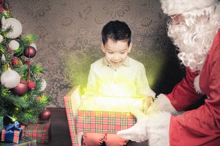 Happy shocked boy surprised to see Santa Claus! Child dressed in red Santa hat. Surprise! Xmas and New Year holiday. Your dad dressed in a Santa Claus costume! Christmas inspirationの写真素材