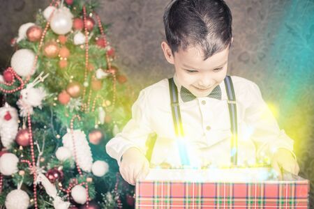 Happy shocked boy surprised to see gift box! Christmas tree. Surprise! Xmas and New Year holiday. Christmas inspirationの写真素材