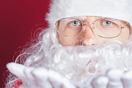 Closeup Santa Claus at Christmas celebration. Red background. New Year celebration holiday. Looking at cameraの写真素材