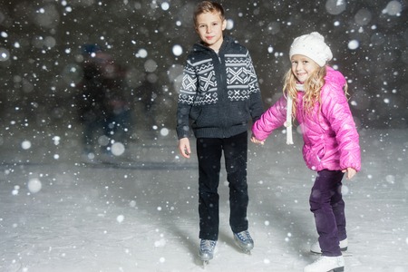 Happy children ice skating at ice rink outdoor, at winter snowy night, sport and healthy lifestyle, ice skating at Holland. Funny kids, boy and girl, sister and brother. Familyの写真素材
