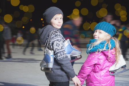 Happy children ice skating at ice rink outdoor, at winter night, sport and healthy lifestyle, ice skating at Holland. Funny kids, boy and girl, sister and brother. Familyの写真素材