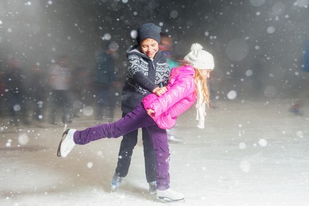 Happy children ice skating at ice rink outdoor, figure skating, at winter snowy night, sport and healthy lifestyle, ice skating at Holland. Funny kids, boy and girl, sister and brother. Family Happy children ice skating at ice rink outdoor, figure skating, at winter snowy night, sport and healthy lifestyle, ice skating at Holland. Funny kids, boy and girl, sister and brother. Family