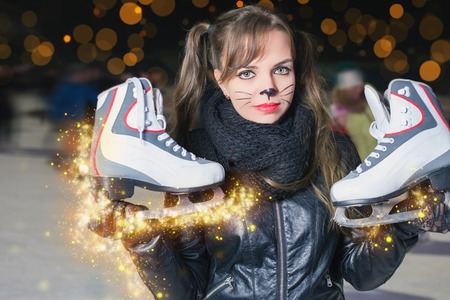 Pretty young woman dressed in cat fancy dress holding skates shoes. Healthy lifestyle and Halloween!...