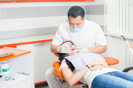 Dentist doctor treats teeth patient girl in dental office. Regular visits to the dentist will save you from tooth decay and you will always have healthy white teeth!の写真素材