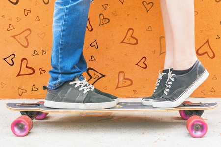 Closeup kissing couple at skateboard and red wall background. Image ready for Valentine's Day, 14th...
