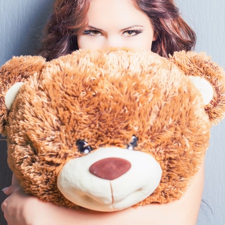 Happy woman received a teddy bear. Blue background.の写真素材
