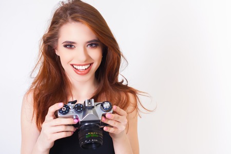 Image of cute girl make a foto selfie at vintage camera. Take a photograph of himself. Funny, party. Beauty. Happy girl smiling. Makeup and hairstyleの写真素材