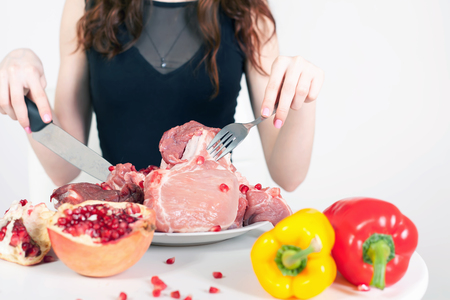 Image of healthy eating. Woman eating flesh meat at restaurant. Cooking meat. There are bell pepper, pomegranate at the table. How to cook?の写真素材