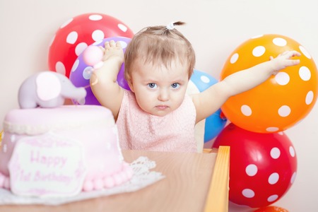 Funny baby celebrating first birthday. Cake is surprise for child. Many balloons! Decoration at home. Make a first wish. Desireの写真素材