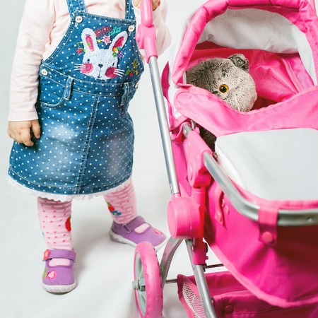 Cute little girl playing with cat toy and baby stroller. Baby carriage. Children's World shop. Baby clothesの写真素材