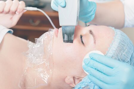 Woman in spa salon receive skin treatment. Facial rejuvenation. Ultrasonic cleaning of the face....