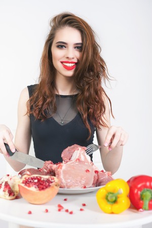 Image of healthy eating. Woman eating flesh meat at restaurant. Cooking meat. There are bell pepper, pomegranate at the table. How to cook?の写真素材