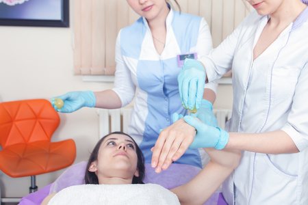 Facial rejuvenation procedure. Beautiful woman in spa salon receiving epilation or correction eyebrow using sugar - sugaring. Doctor. Practice for the intern.の写真素材