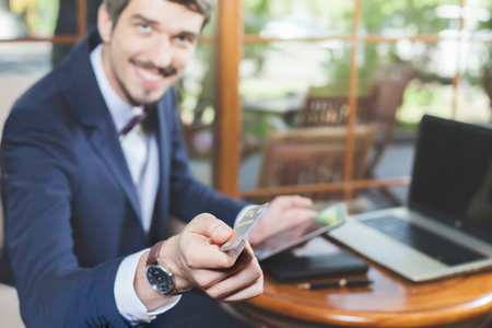 Concept of online payment by plastic card through the Internet Banking. Human hand for mobile phone and holding credit card, man pays the bill. Laptop at table. Successful businessmanの写真素材