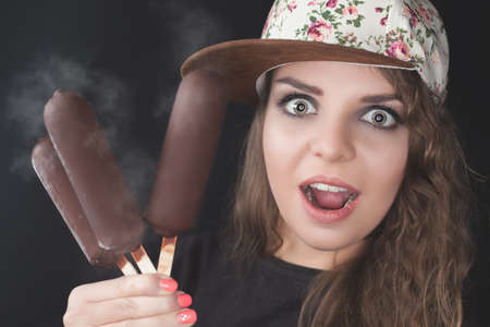 Surprised teenage girl holding several ice cream with chocolate.の写真素材