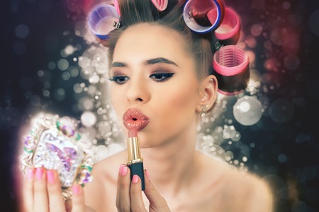 Beautiful girl doing make-up, using lipstick, make hairstyle. Fashion. Use a mirror