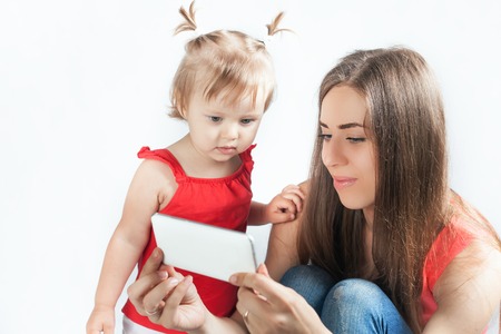 Image of funny baby and mother make selfie photo on mobile phone. Newborn looking at the camera surprised! Mothercare is most important in baby lifeの写真素材