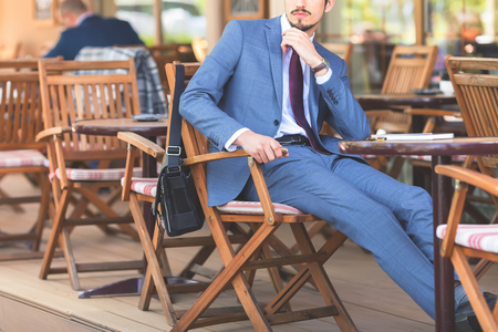 Handsome male has a french breakfast at sidewalk cafe outdoors. Smiling businessman. Elegant successful man. Has a mustacheの写真素材