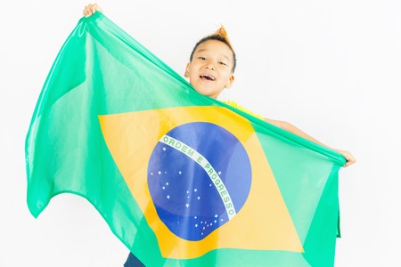 Brazilian patriot boy holding Brazil flag. Football or soccer championship. Support fan. White backgroundの写真素材
