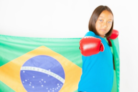 Brazilian patriot and fan girl holding Brazil flag. Brazilian boxing championship. Wearing a boxing gloves. Boxer. Battle. White backgroundの写真素材