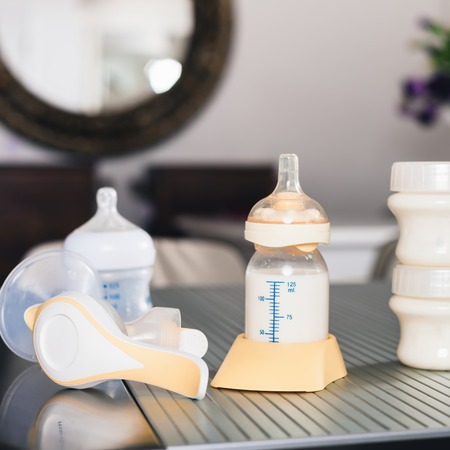 Baby bottle with milk and manual breast pump. A lot of full bottles with breast milk on the background. Mother's milk - the most healthy food for newborn or infantの写真素材