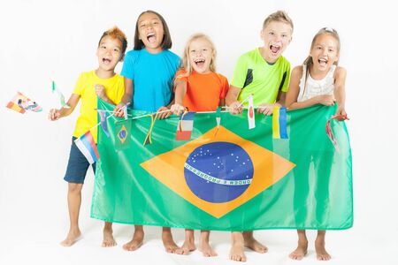 Group of children holding a Brazil flag and international flags. Rio de Janeiro at Brazil. Happy fans of kids watching tv. Multiracial people. Volunteerの写真素材