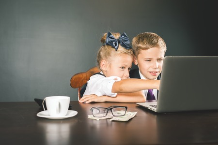 Business or school kids uses a laptop computer. Concept of work at office. Motivate your child to study boring subject. Forex. Children dressed in school or business uniform. Studentの写真素材