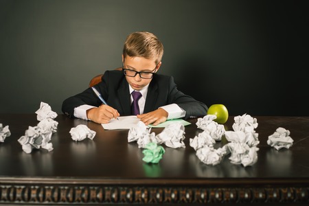 Inspired school boy writing essay or exam. Bloger has a good idea and writing it.