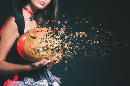 Closeup of sexy woman with gothic makeup smokey eyes. Holding a pumpkin. Vampire, evil. Goth. Secret. Fashion. Hot babe. Halloween party masquerade. Pixelated, photo pixelの写真素材