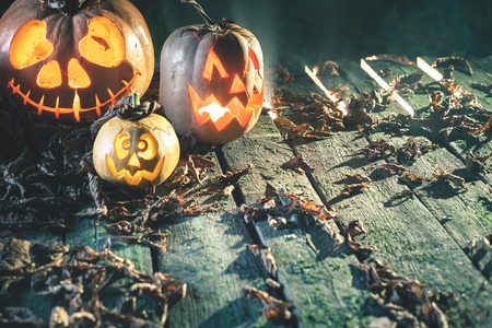 Halloween pumpkins at wood background. Carved scary faces of pumpkin. Night horror. October holiday....