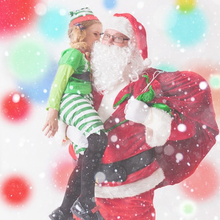 Christmas Wish 2016. Santa Claus and Little Girl dressed in Elf costume. Telling Wishes in Santa Claus's Ear. Cristmas Scene at White Backgroundの写真素材