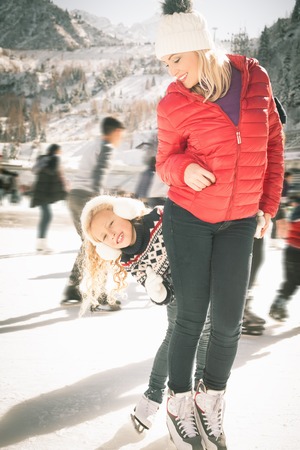 Happy family outdoor ice skating at rink. Mother and daughter has winter activities. Mom, kids....