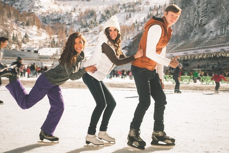 Image of group funny teenagers girls and boy ice skating outdoor at ice rink, looking at camera. Medeo stadium. Almaty. Winter activities for good mood and healthy mind. Healthy lifestyle and sportの写真素材
